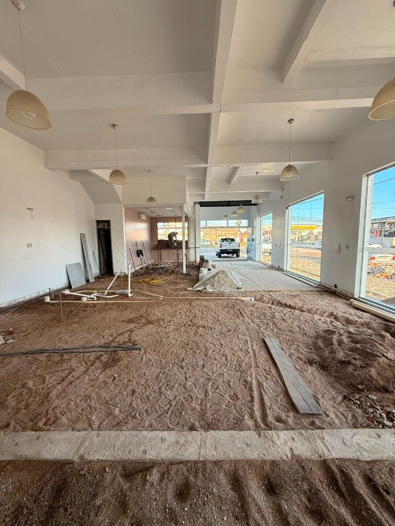 Salão principal do hub M3VOLT em obra — preparação do piso e hidráulica